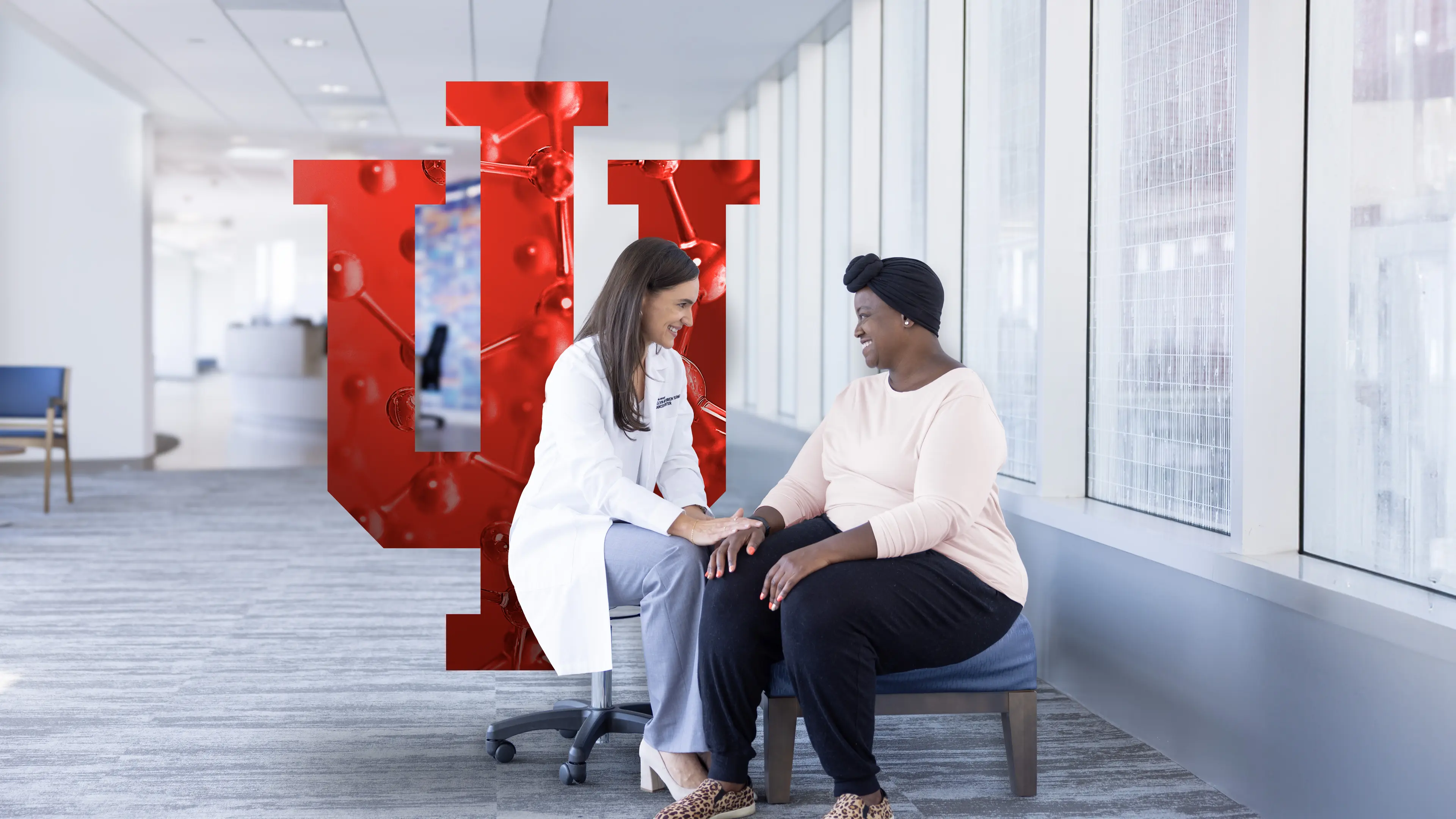 Dr. Tarah Ballinger, MD, sits with a black female breast cancer patient in the bright lobby of the Simon Cancer Center.