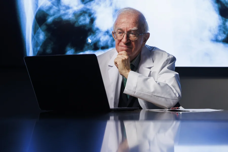 Dr. Lawrence Einhorn, an IU Distinguished Professor and oncologist, sits at his computer, smiling.