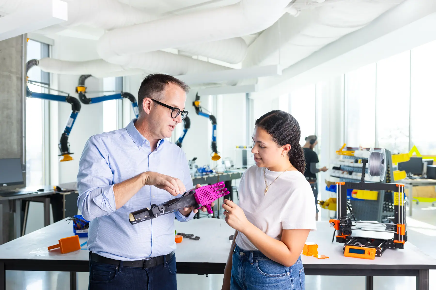 John Racek demonstrates a prosthetic arm to a female student at the Luddy SICE Protolabs.