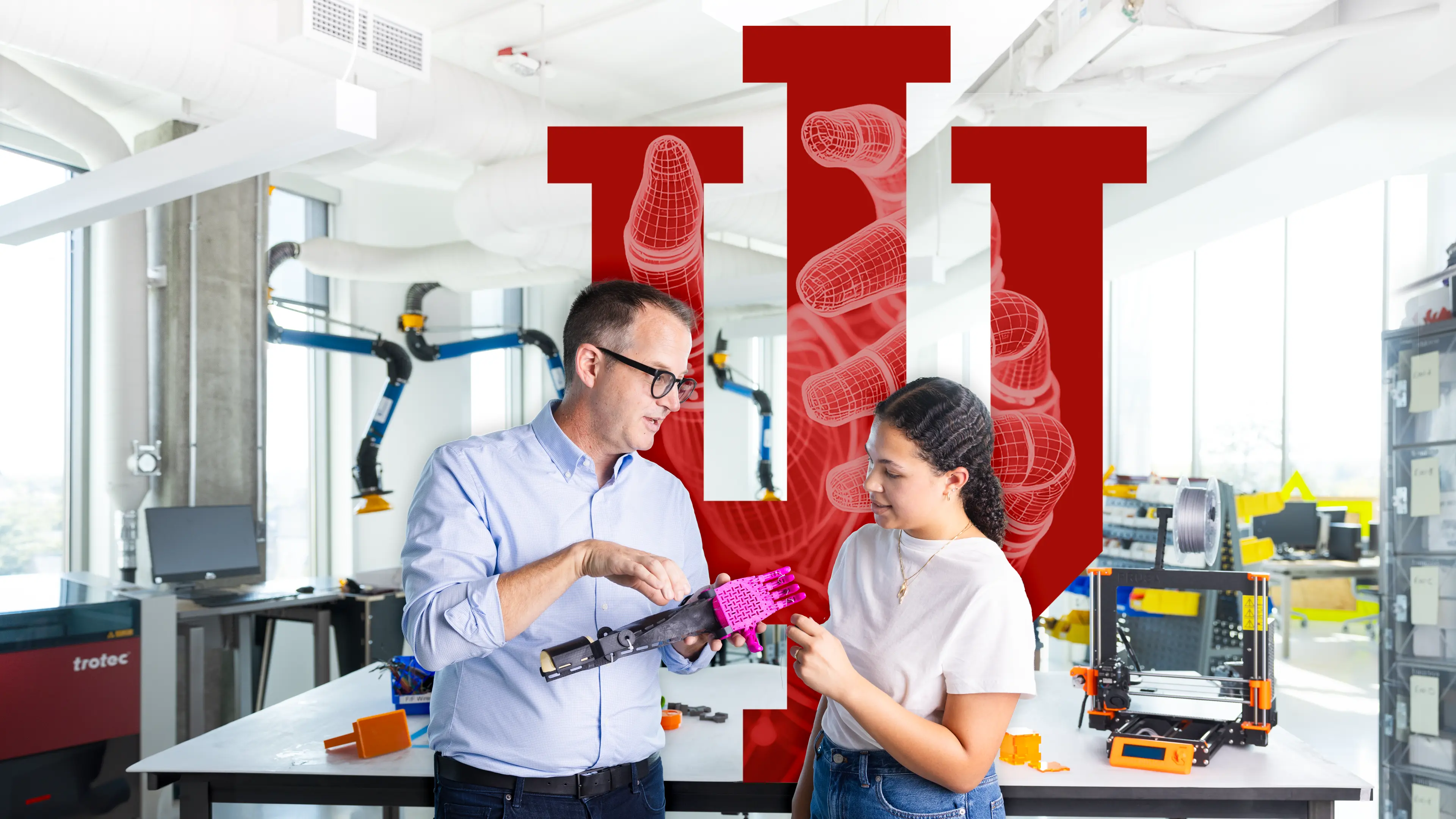 John Racek demonstrates a prosthetic arm to a female student at the Luddy SICE Protolabs.