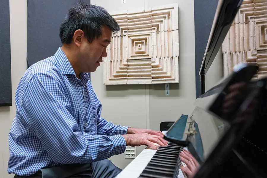 Timothy Hsu, assistant professor of music technology at the Herron School of Art and Design, plays the piano inside a sound booth featuring a sustainable acoustic panel made from mycelium, the root-like structure found in fungi.