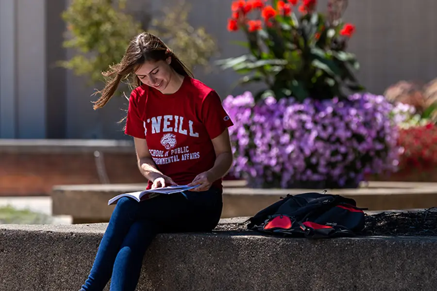 A female student sits outside of the Paul H. O'Neill School of Public and Environmental Affairs at Indiana University Bloomington