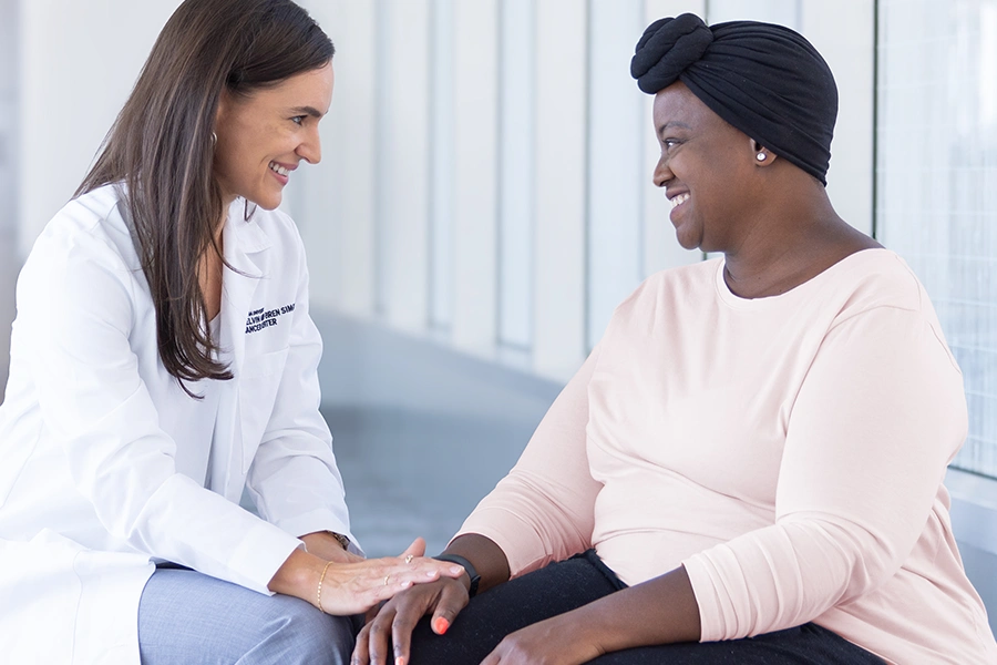 A doctor shares a moment of conversation with a cancer patient in a modern healthcare lobby.