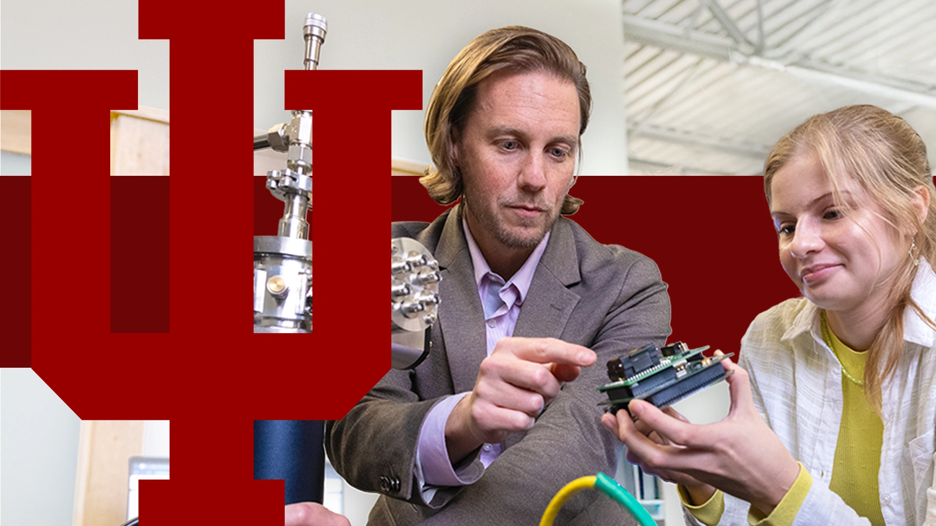 faculty member and student working with microelectronics with large crimson trident overlayed