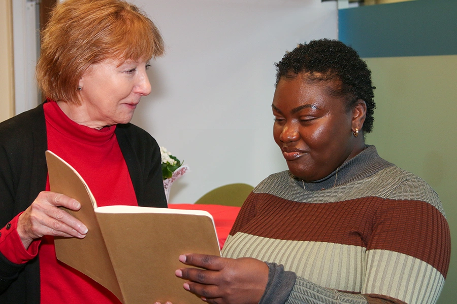 A female researcher shares a book with a female healthcare worker