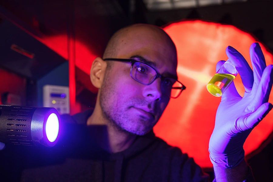 a scientist shines a light on a test tube in a dimly lit lab