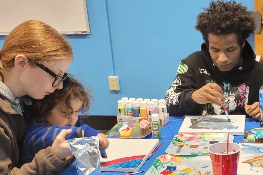 a mother and father at a craft table with their young child