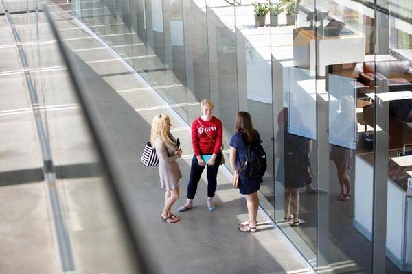 Three female students standing in a long curved hallway on the IU Columbus campus.