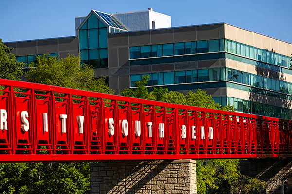 A red bridge with lettering on the side that says 'Indiana University South Bend'