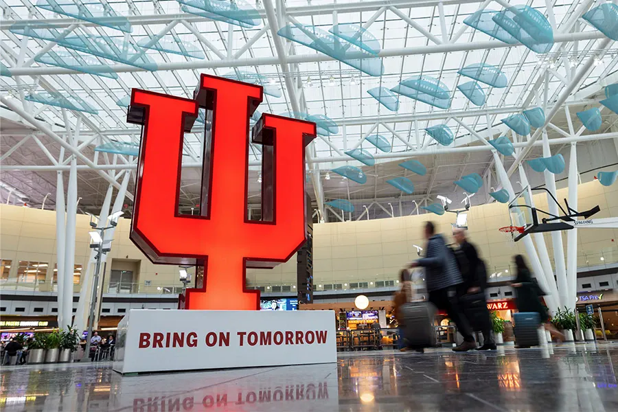 A large IU trident sculpture sits inside an airport lobby.