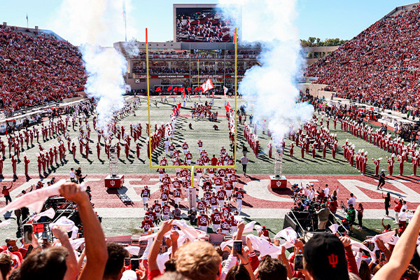 IU football players walking onto field surrounded by cheering fans