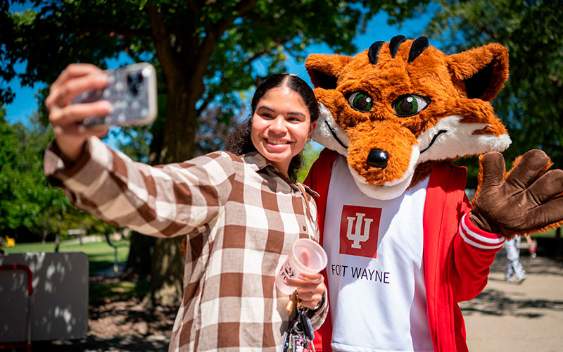 An IU Fort Wayne student takes a selfie with the IUFW mascot, Ruby the Red Fox.